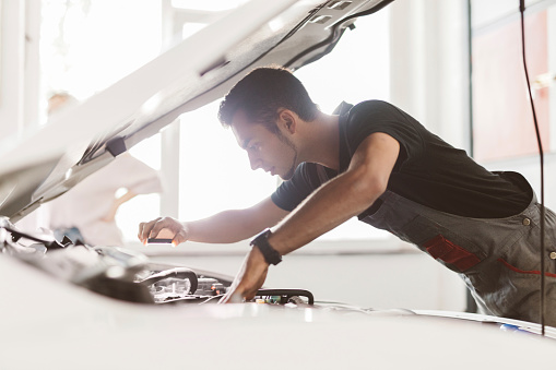 Young man under the hood of a car