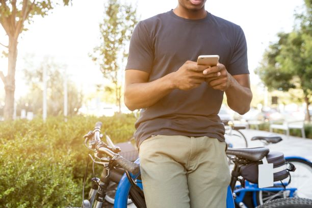 Man leaning against bicycle on his cell phone