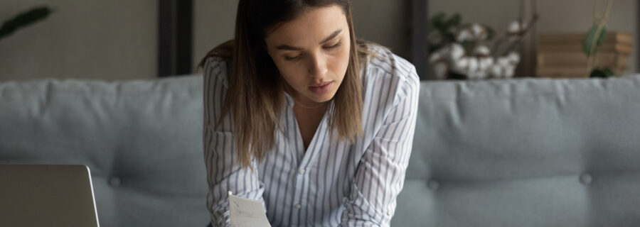 A young woman reviews her bills to see if she should apply for a personal loan to build credit.