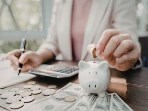 Person putting money in piggy bank indicating saving money from tax refund