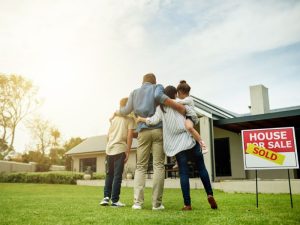 Family standing in front of their new house after purchasing it.