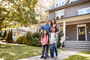 Family of four smiling in front of their new home in the Hudson Valley, holding house keys